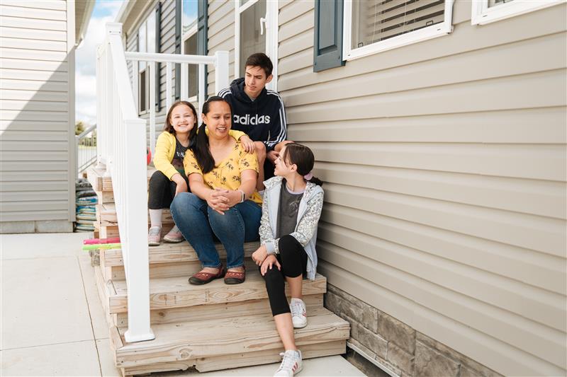 family sitting on steps outside home